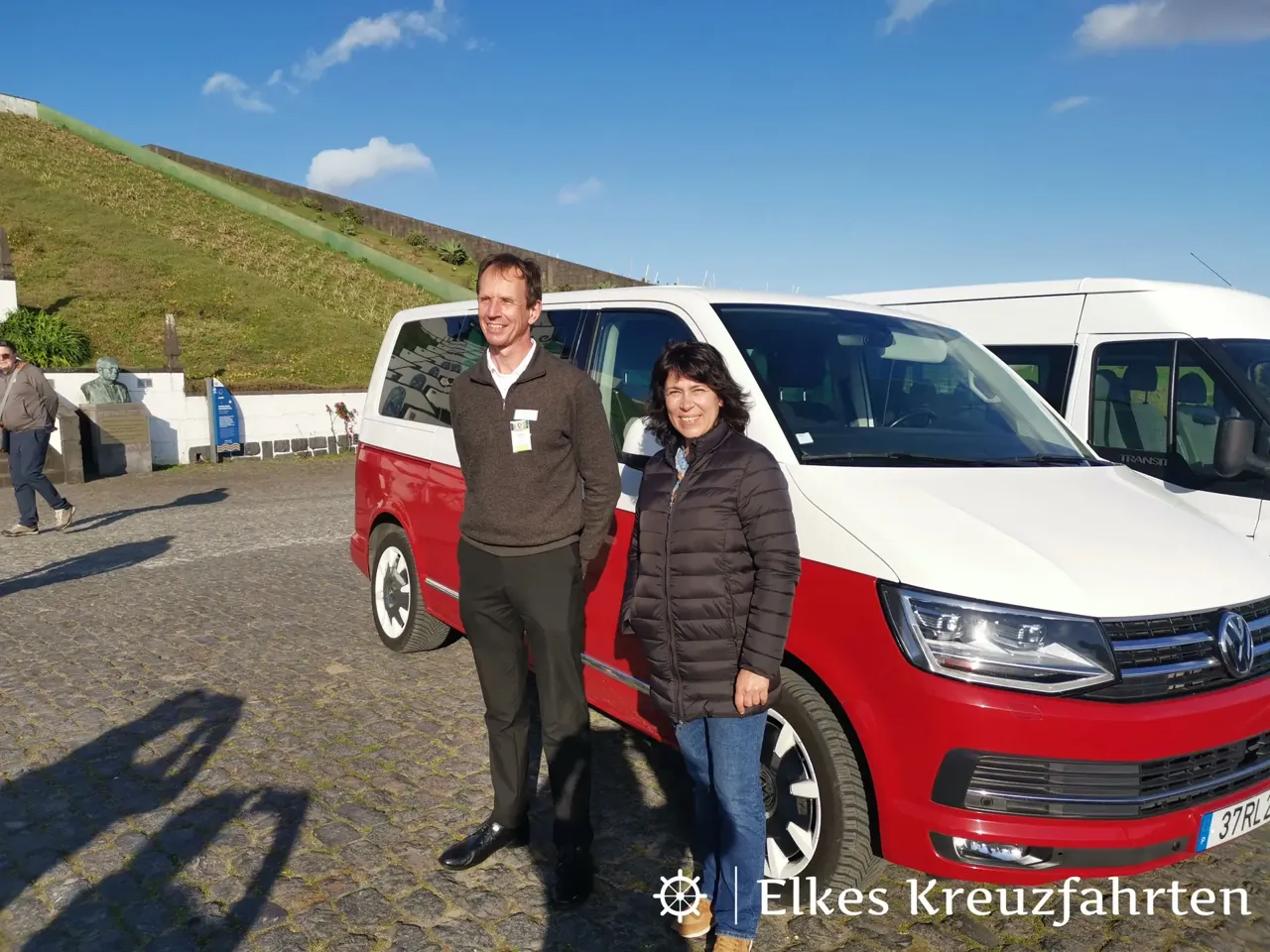 Zwei Personen vor einem rot-weißen Kleinbus bei einer Tour mit örtlichem Anbieter